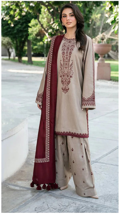 Woman wearing a beige and maroon embroidered traditional outfit in an outdoor setting.