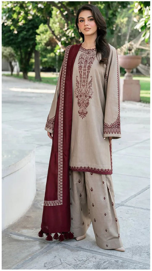 Woman wearing a beige and maroon embroidered traditional outfit in an outdoor setting.